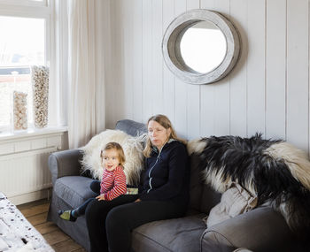 Woman sitting with granddaughter on sofa at home