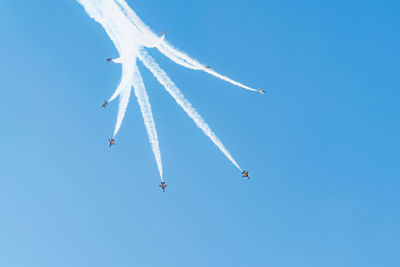 Low angle view of airshow against clear blue sky