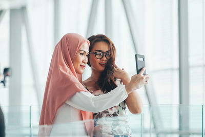 Smiling women sharing smart phone