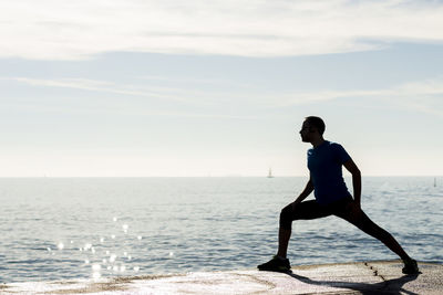 Man exercising against sea at beach