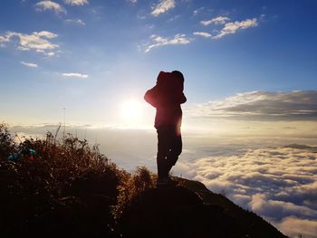 Silhouette man standing on rock against sky during sunrise