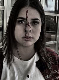 Close-up portrait of young woman with blood on face