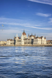 Buildings by river against sky