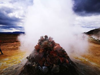 Steam emitting from geyser against sky