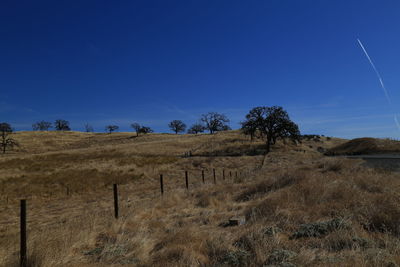 View of fields against clear blue sky