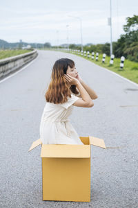 Woman with umbrella standing on road in city