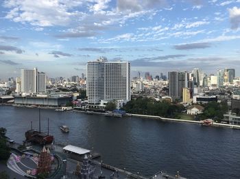 Buildings by river against sky in city