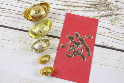 High angle view of ingot feng shui and red card on table