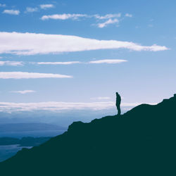 Silhouette woman standing on mountain against sky