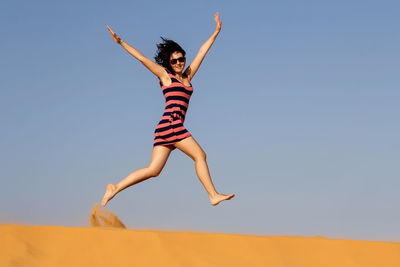 Low angle view of woman jumping in mid-air