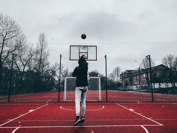 Rear view of man standing on pole against basketball 