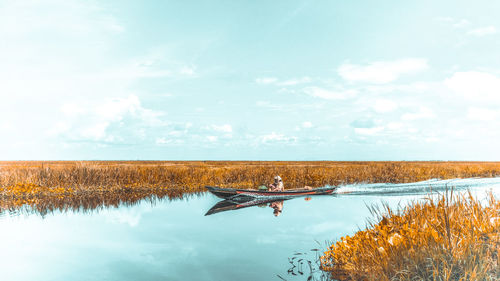 Man in boat on river against sky