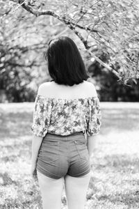 Rear view of woman standing against branches at park