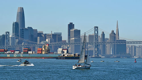 Sailboats in river against buildings in city