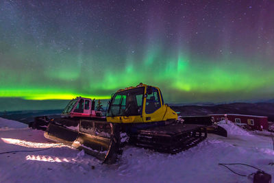 View of illuminated snow covered field against sky at night