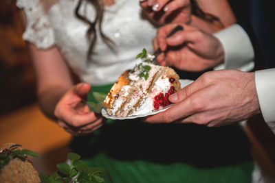 Midsection of couple eating cake in party