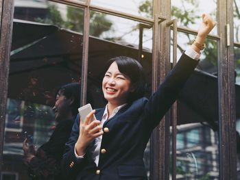 Close-up of woman holding mobile phone while standing in office