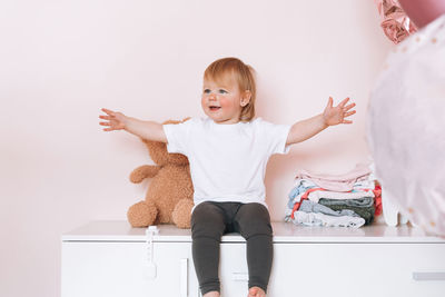 Cute funny baby girl happy child in home clothes sitting on commode at home