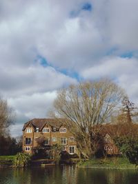 Houses and trees by river against sky