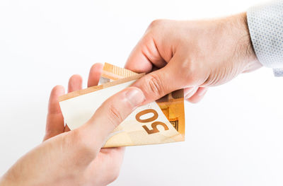 Close-up of man holding hands over white background