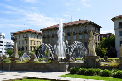 Fountain in city against sky