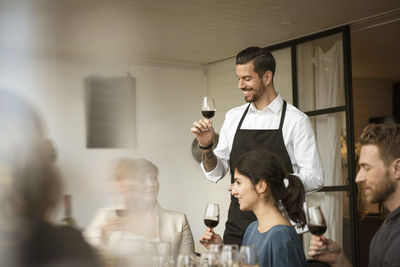 Smiling people holding wineglass while discussing at table