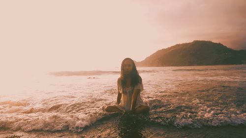 Woman on beach against sky during sunset