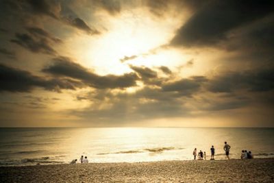 Silhouette people on beach against sky during sunset