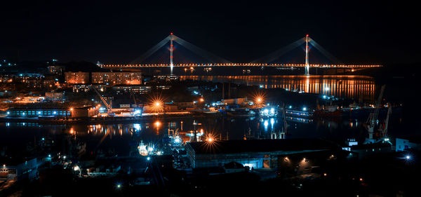 Illuminated bridge over river in city at night