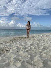 Full length of woman in bikini at beach against sky