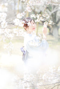 Full length of woman on white flowering plant