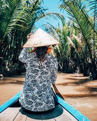 Rear view of woman rowing while sitting on boat in river