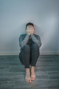 Man crying while covering his face with hands sitting on the floor