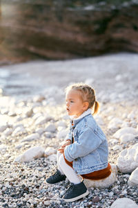 Full length of cute boy sitting on rock