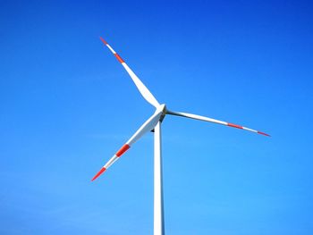 Low angle view of windmill against clear blue sky