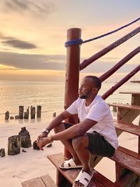 Rear view of woman standing at beach during sunset