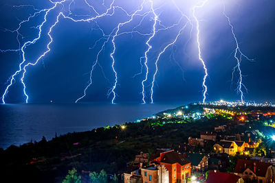 Lightning over illuminated cityscape against dramatic sky