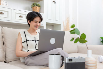 Portrait of young woman using laptop at home