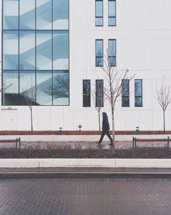 Side view of man walking on footpath against building