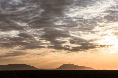 Scenic view of silhouette mountains against sky at sunset