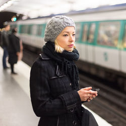 Beautiful woman standing at railroad station during winter