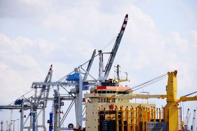 Cranes at commercial dock against sky