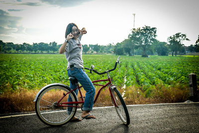 Full length of woman with bicycle on field against sky