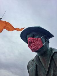 Close-up portrait of sculpture against sky