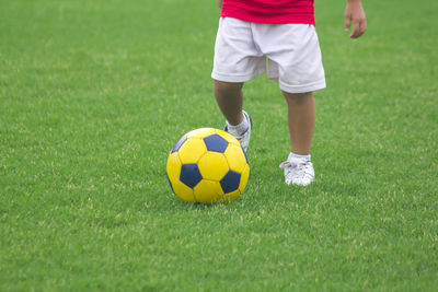 Low section of boy playing soccer on field