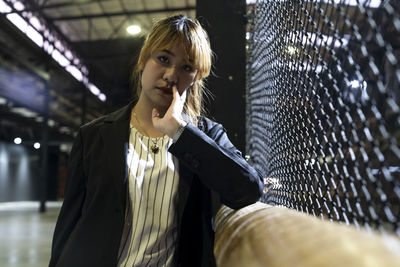 Portrait of sad businesswoman standing by fence at railroad station