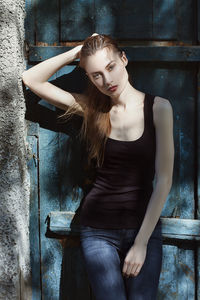 Portrait of confident woman leaning wooden door