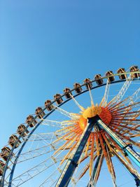 Low angle view of ferris wheel against clear blue sky