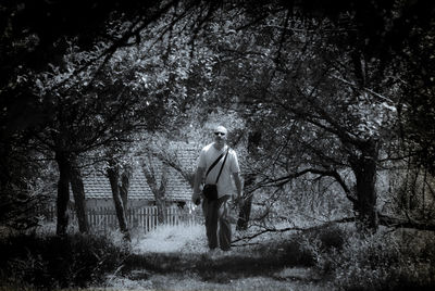 Mature man walking amidst trees on grassy field
