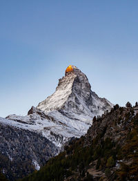 Low angle view of snowcapped mountains against clear sky